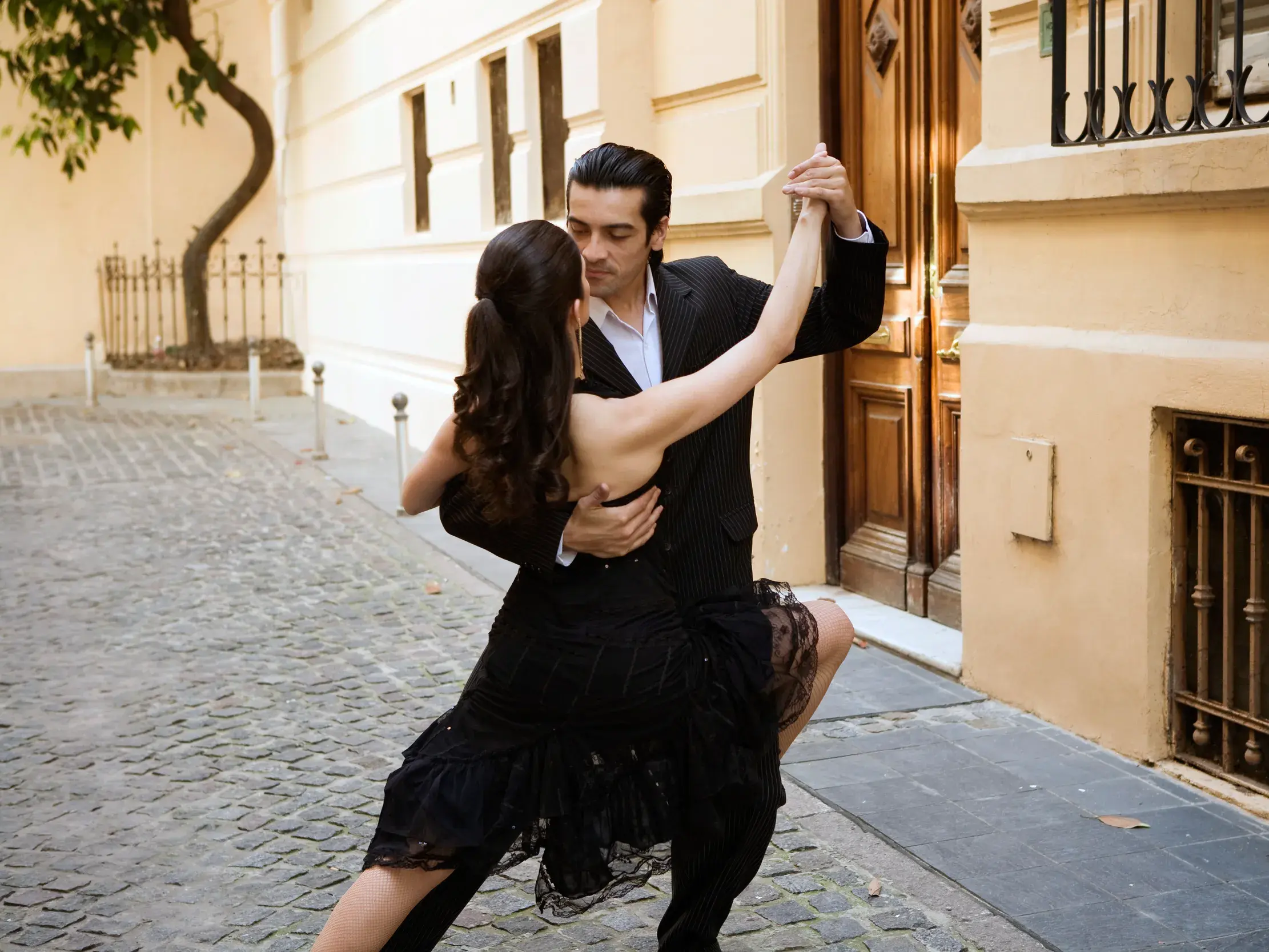 Ein Paar tanzt leidenschaftlich Tango auf einer Kopfsteinpflasterstraße in einem historischen Viertel von Buenos Aires.