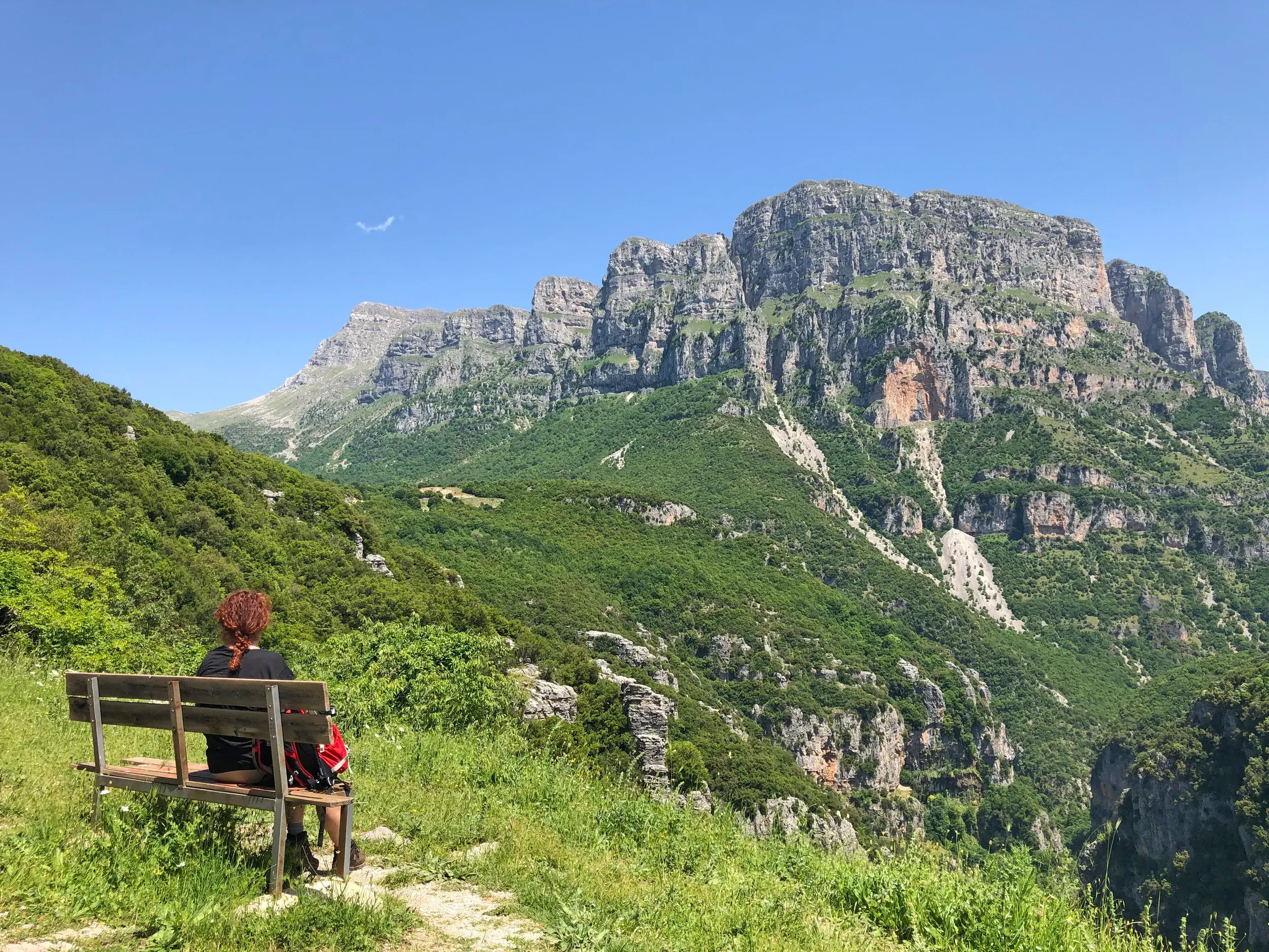 Eine Wanderin genießt auf einer Trekking-Reise in Griechenland die Aussicht vom Wanderweg auf die Felswände des Astraka-Berges.