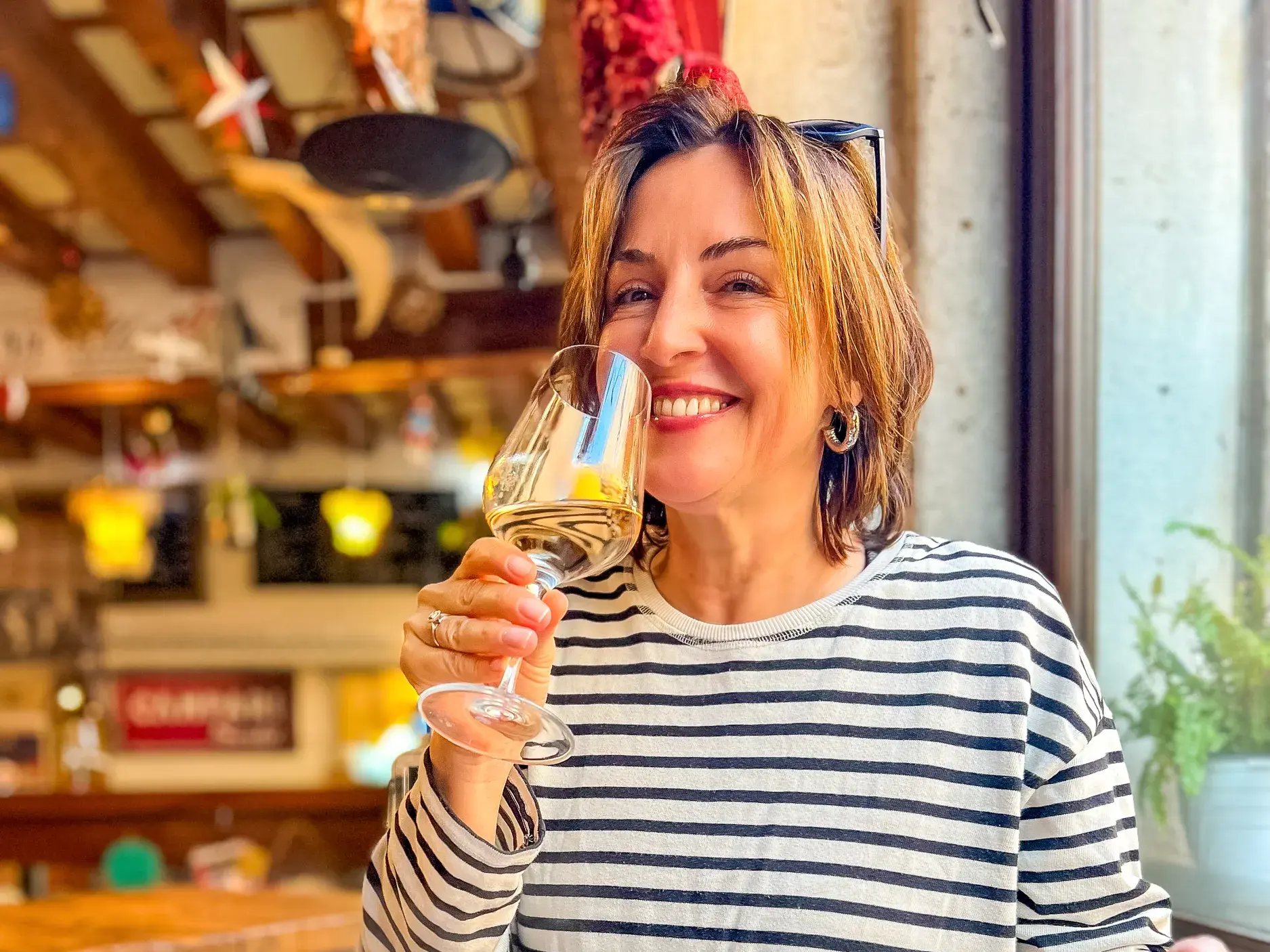 Lächelnde Frau genießt ein Glas Weißwein in einem Restaurant bei der Reise durch das Périgord