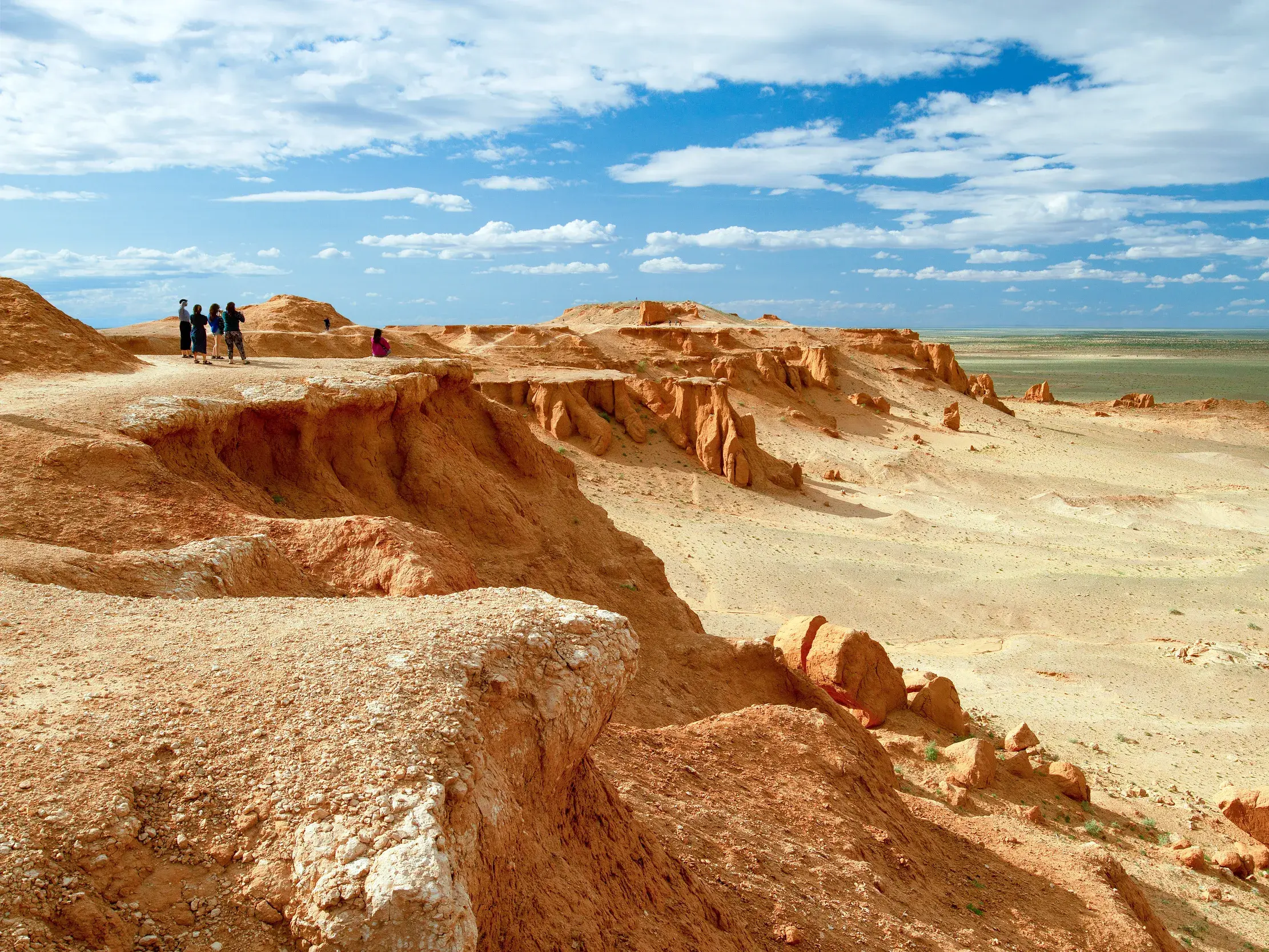 Junge Reisegruppe auf Entdeckertour an den Klippen der Flammenden Felsen von Bayanzag in der mongolischen Gobi-Wüste.