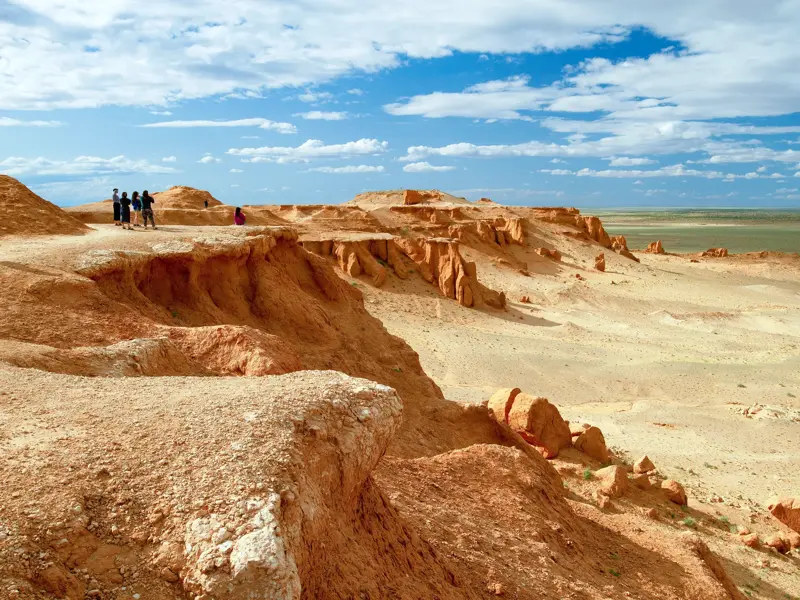 Junge Reisegruppe auf Entdeckertour an den Klippen der Flammenden Felsen von Bayanzag in der mongolischen Gobi-Wüste.