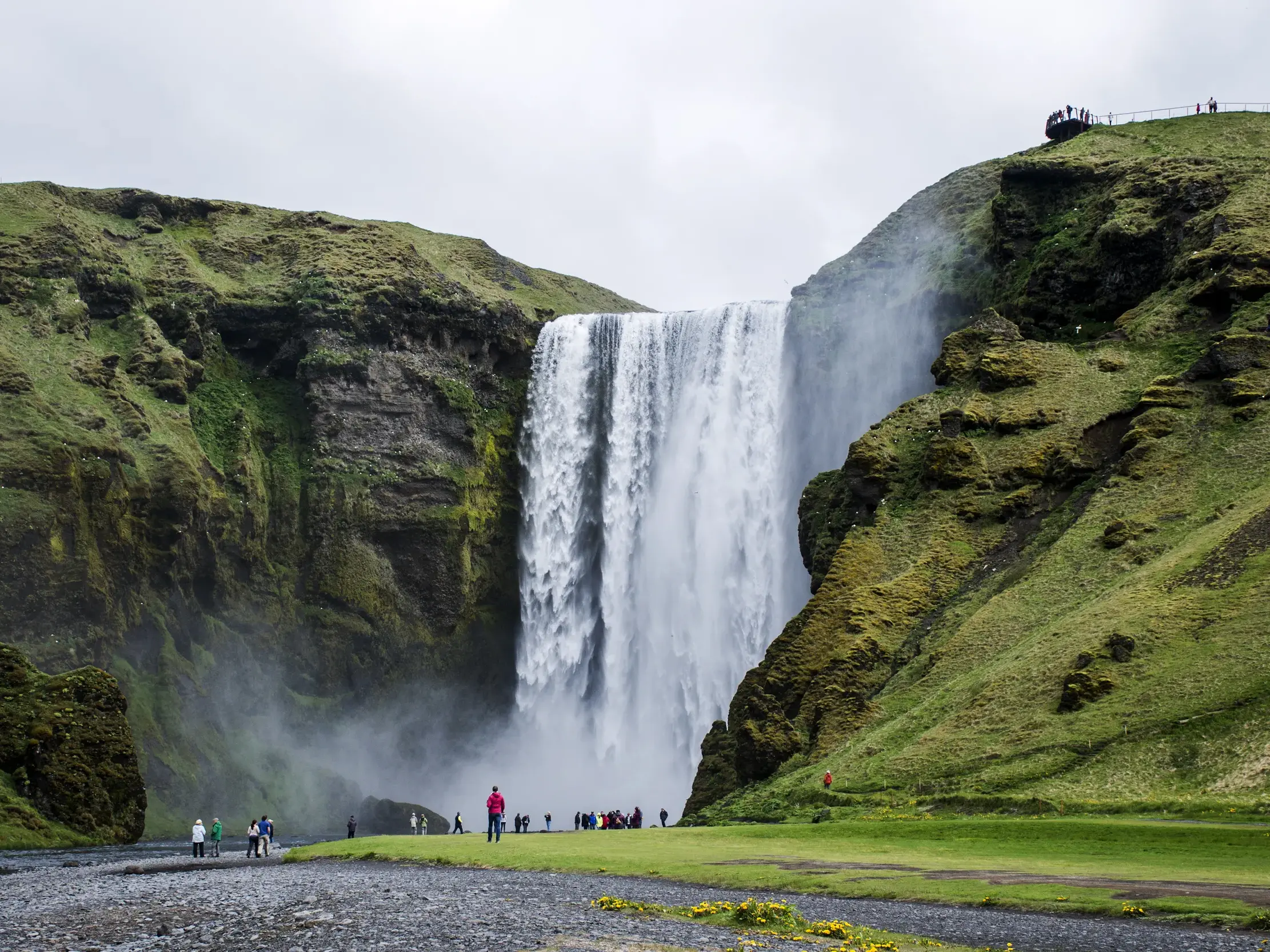 Majestätischer Skogafoss Wasserfall an Islands Südküste, an dessen Fuß Wanderer die gewaltigen Wassermassen bestaunen.