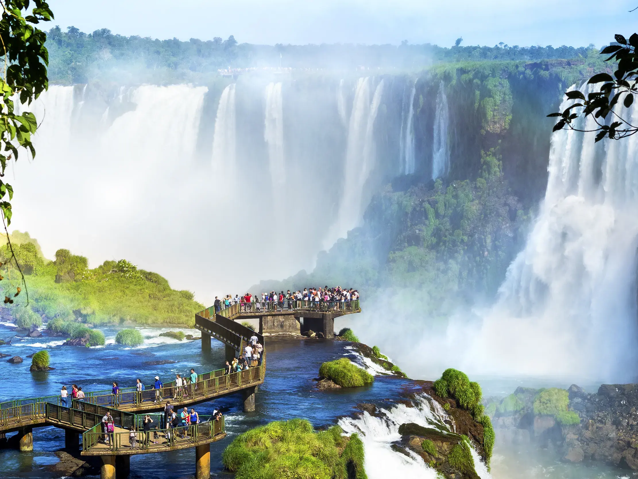 Reisegruppe auf hölzernen Stegen vor den tosenden Iguazú-Wasserfällen, einem UNESCO-Welterbe in Brasilien.