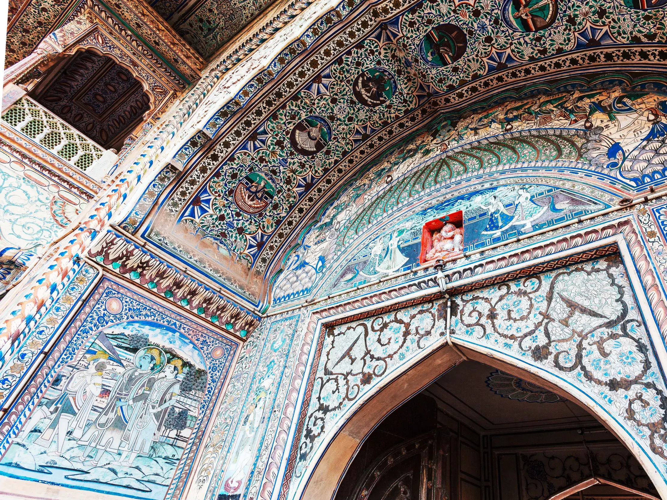 Farbenprächtige Fresken mit Götterdarstellungen und floralen Mustern zieren die Gewölbedecke des Fort Amber in Jaipur.