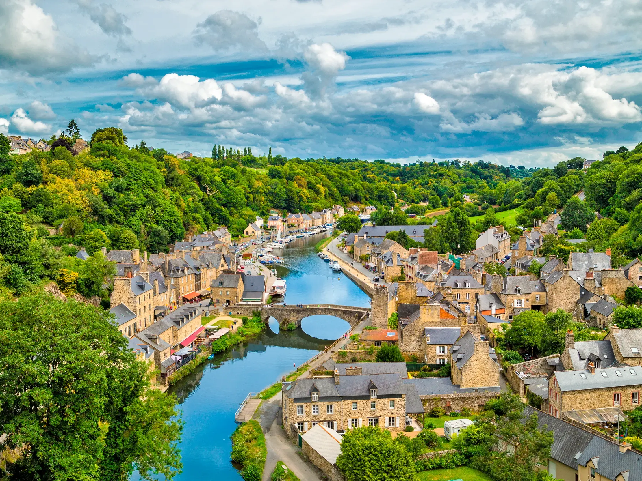 Panoramablick auf die Altstadt von Dinan in der Bretagne mit Fachwerkhäusern und Brücke über den idyllischen Flusshafen.