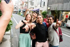 Eine Gruppe junger Leute auf einer geführten Rundreise posiert lachend für ein Foto in einer Straße in Tokio.