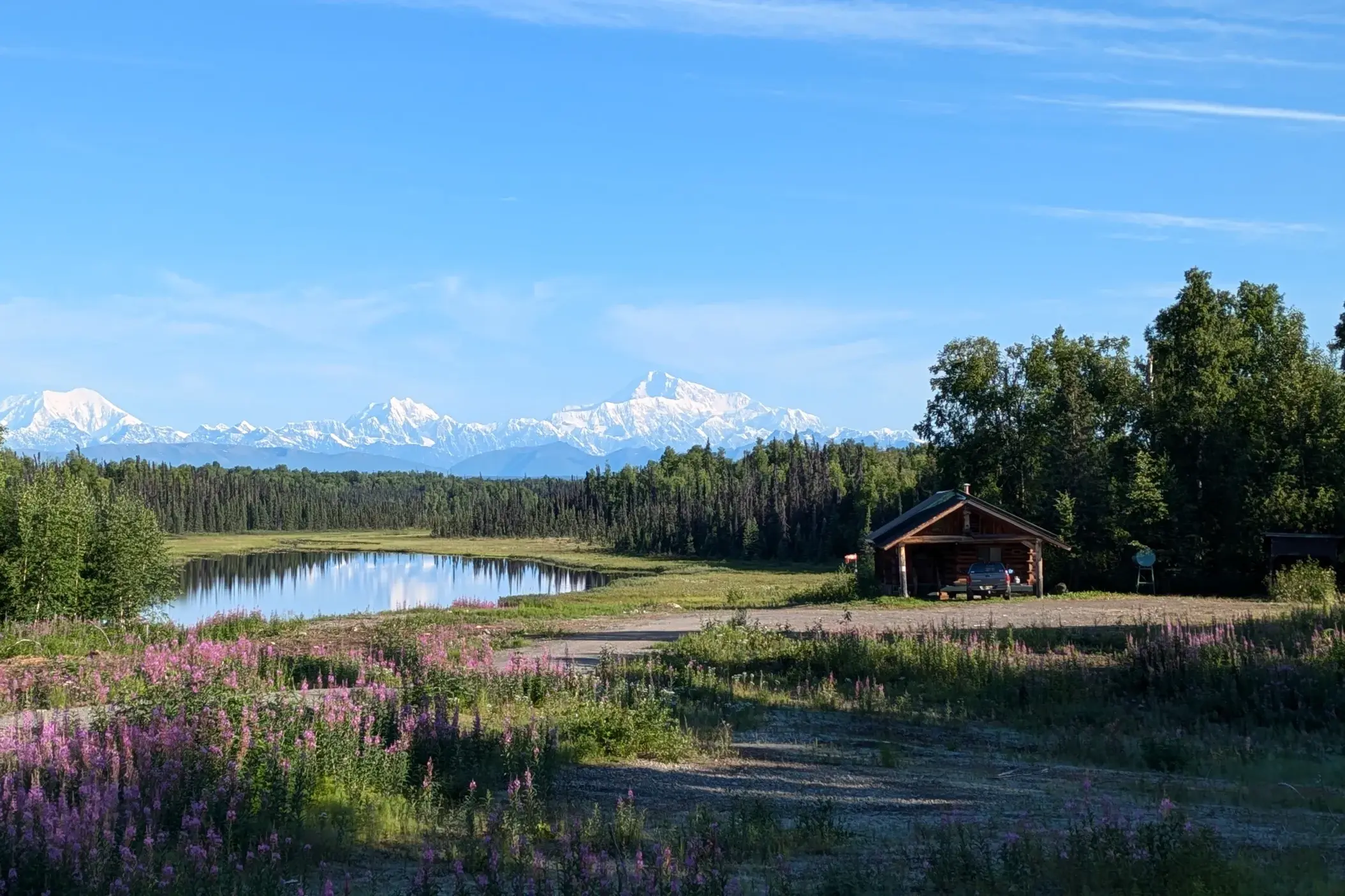 Rustikale Blockhütte an einem See in Alaskas Wildnis bei Talkeetna mit Blick auf die schneebedeckte Alaska Range und Mt. Denali.