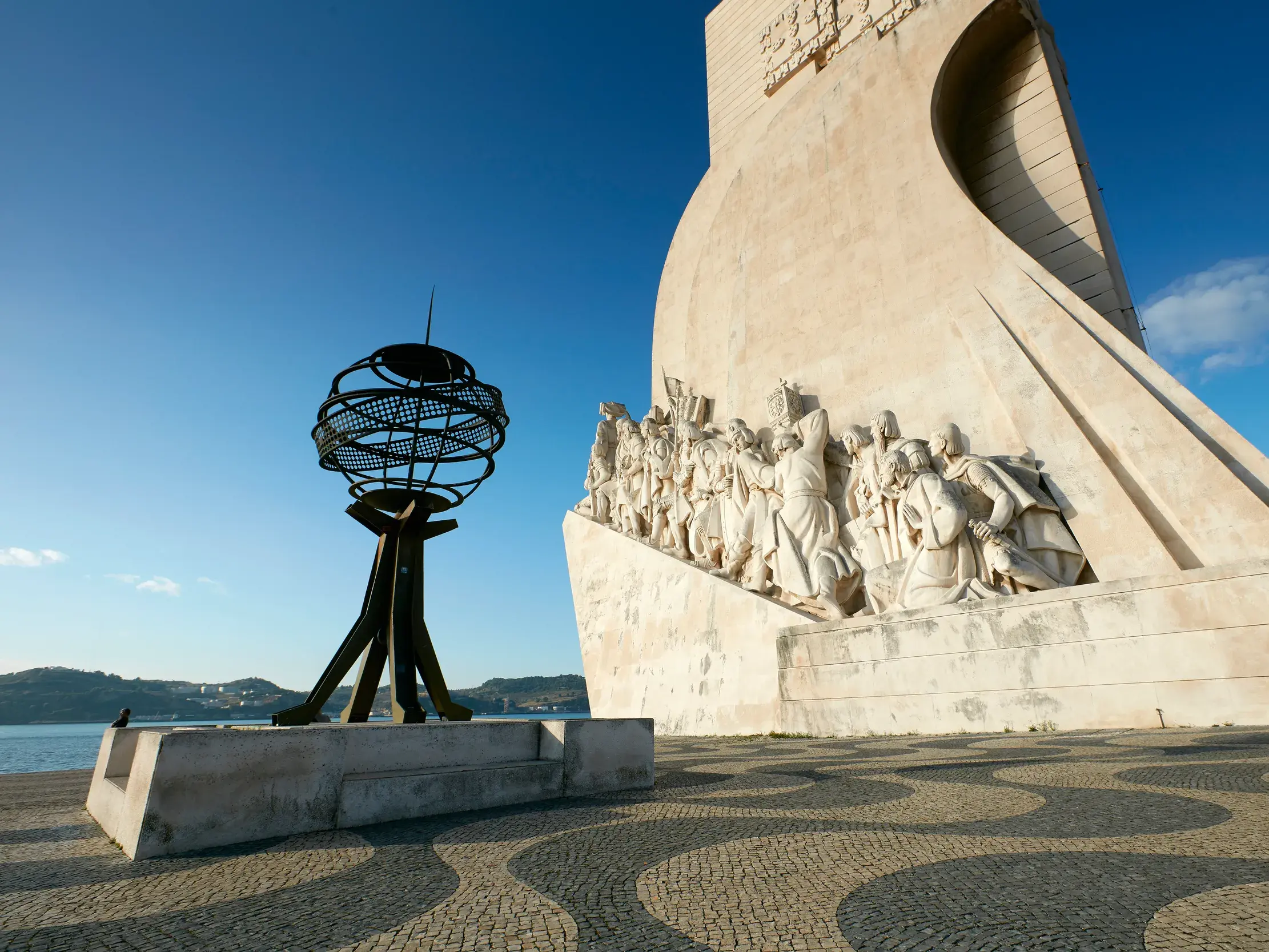 Das Entdeckerdenkmal in Lissabons Stadtteil Belém mit der Statue von Heinrich der Seefahrer und Mosaikpflaster bei Tag.