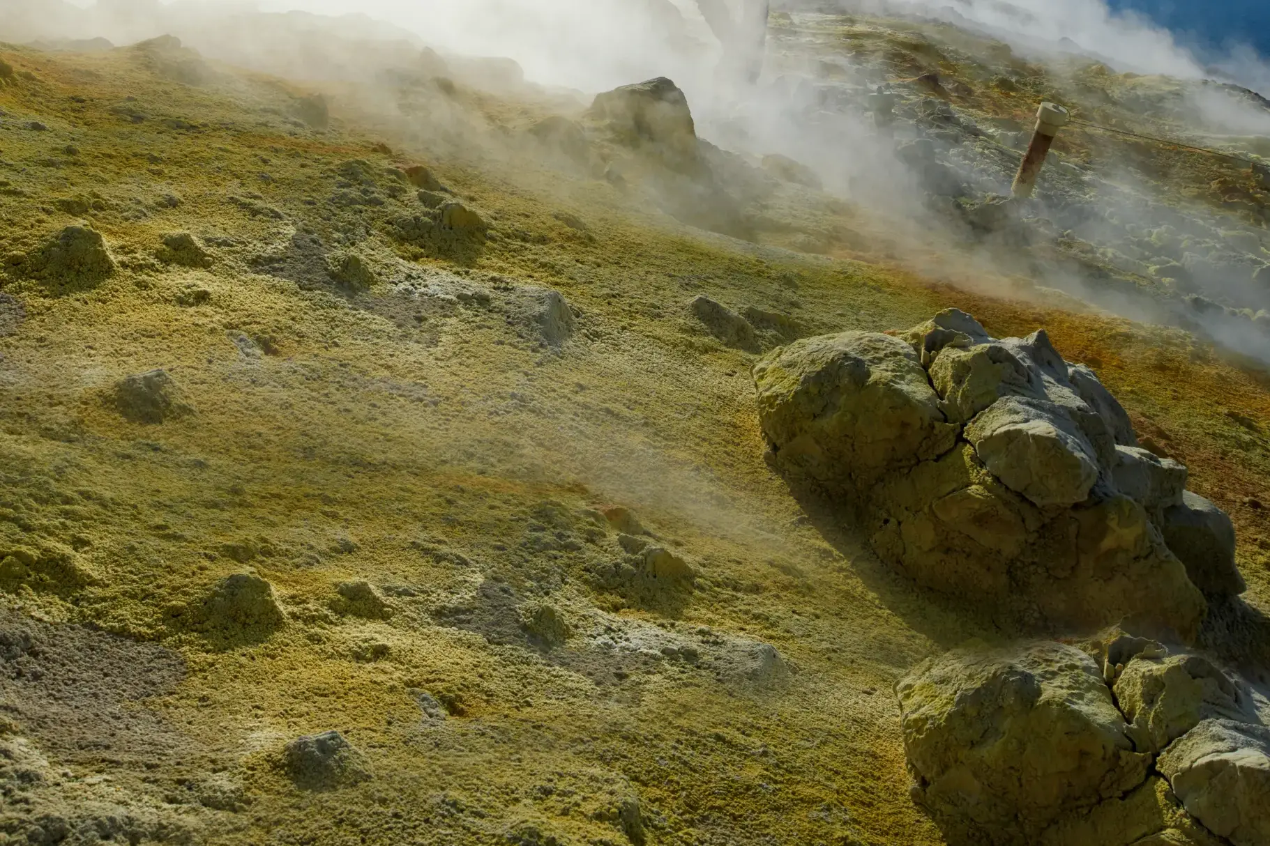 Gelbe Schwefelablagerungen und aufsteigende Fumarolen an einem nebligen Hang des Vulkans auf der Äolischen Insel Vulcano.