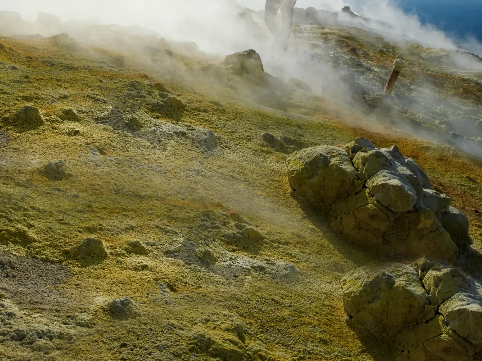 Gelbe Schwefelablagerungen und aufsteigende Fumarolen an einem nebligen Hang des Vulkans auf der Äolischen Insel Vulcano.