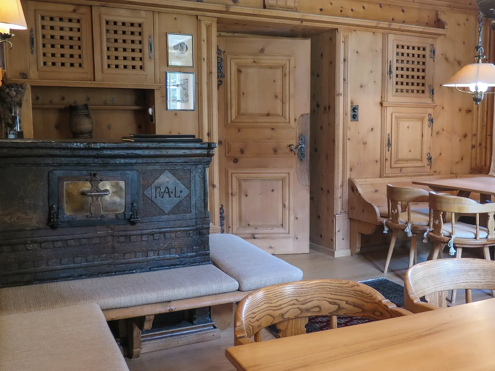 Rustikale Gaststube mit Holztäfelung, Eckbänken und einem traditionellen Kachelofen im Berghotel in Bivio.