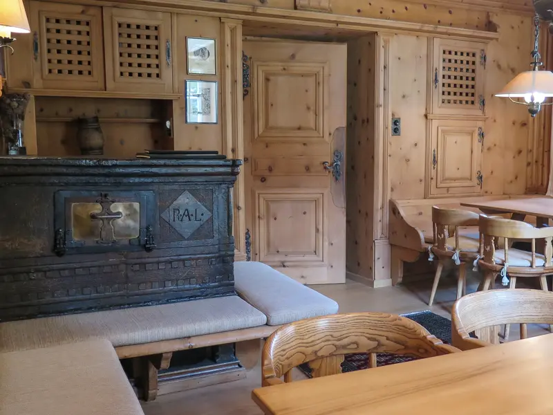Rustikale Gaststube mit Holztäfelung, Eckbänken und einem traditionellen Kachelofen im Berghotel in Bivio.