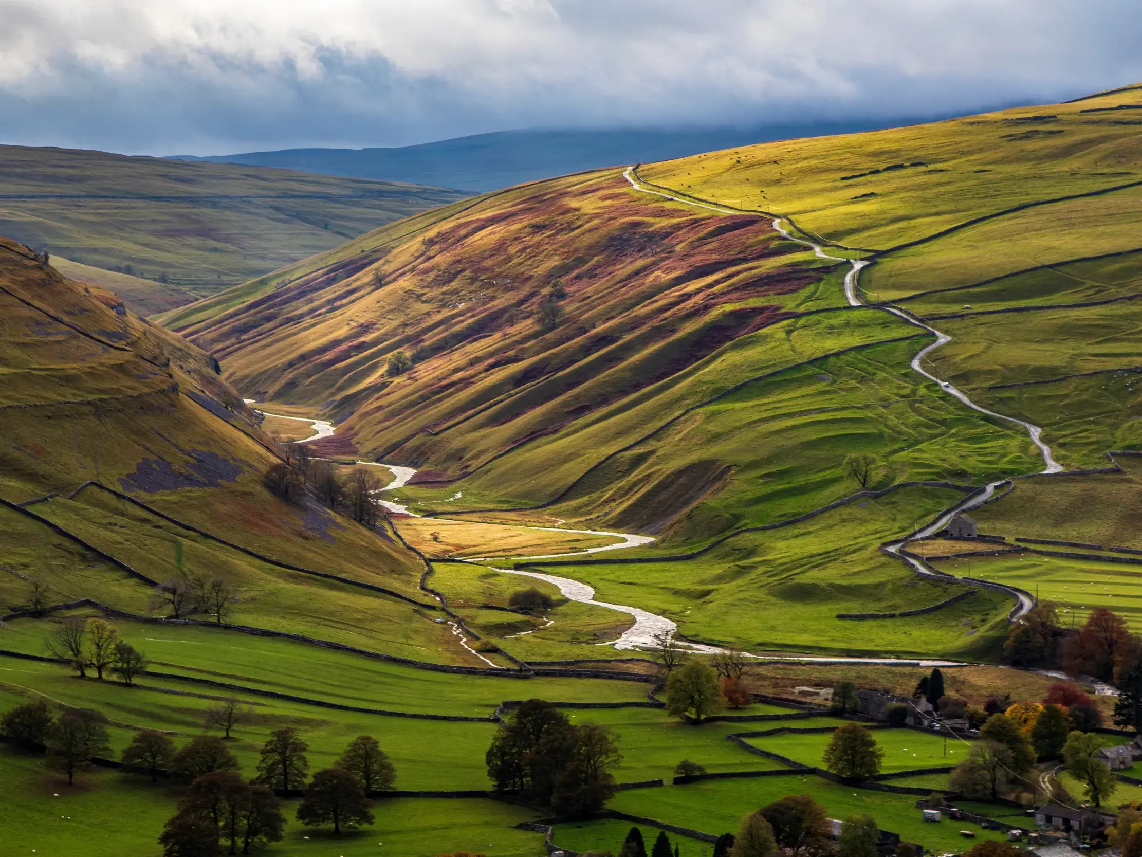Malerischer Blick auf das grüne Tal Swaledale mit Steinmauern und Wanderpfad beim Trekking im Yorkshire Dales Nationalpark.