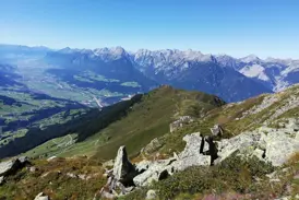 Sonnige Panoramasicht von einem Wanderweg über das weite Zillertal auf die schroffen Gipfel der Zillertaler Alpen.
