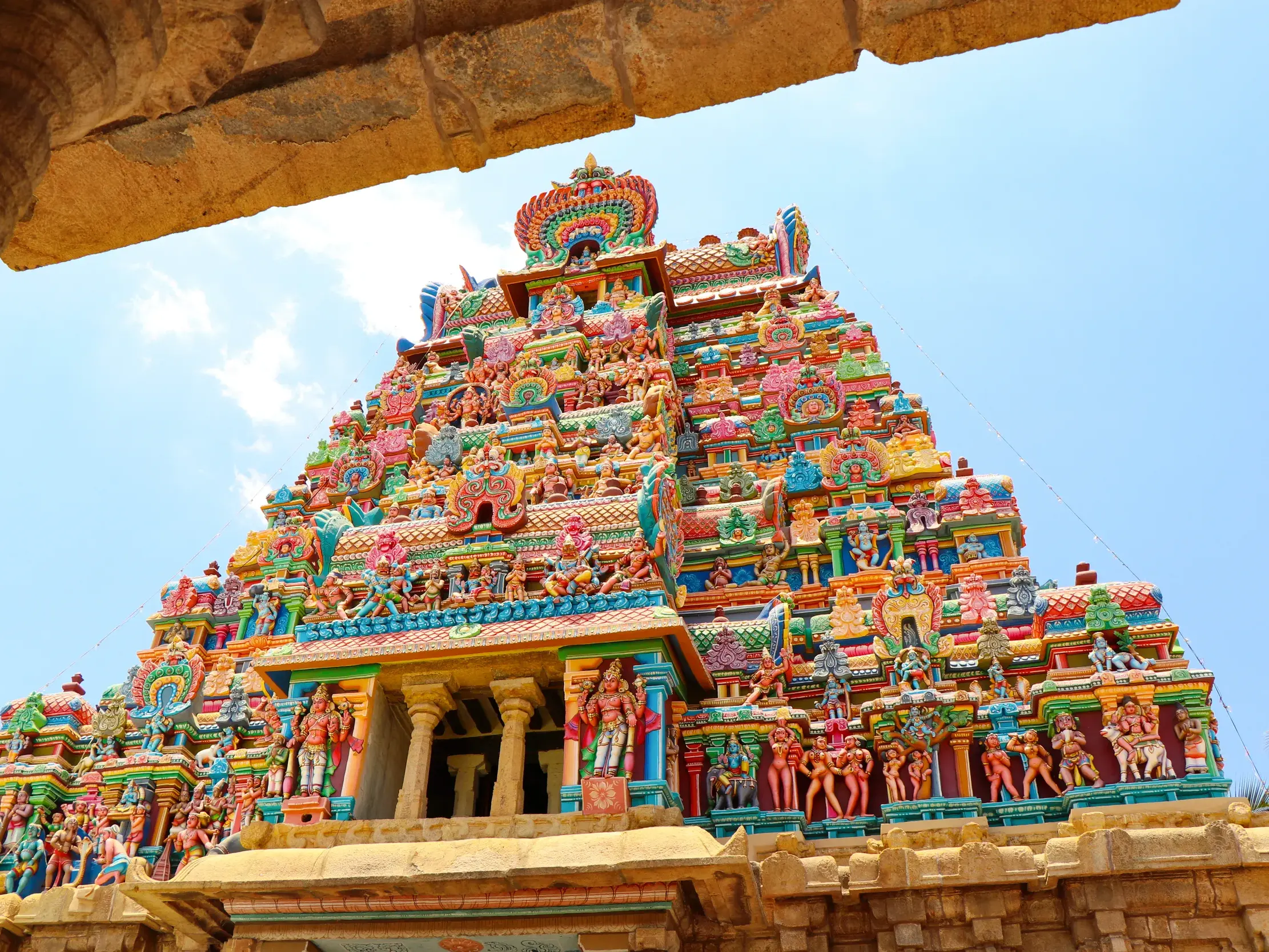 Farbenprächtiger, mit Götterfiguren geschmückter Gopuram des Ranganathaswamy-Tempels in Srirangam gegen den blauen Himmel.