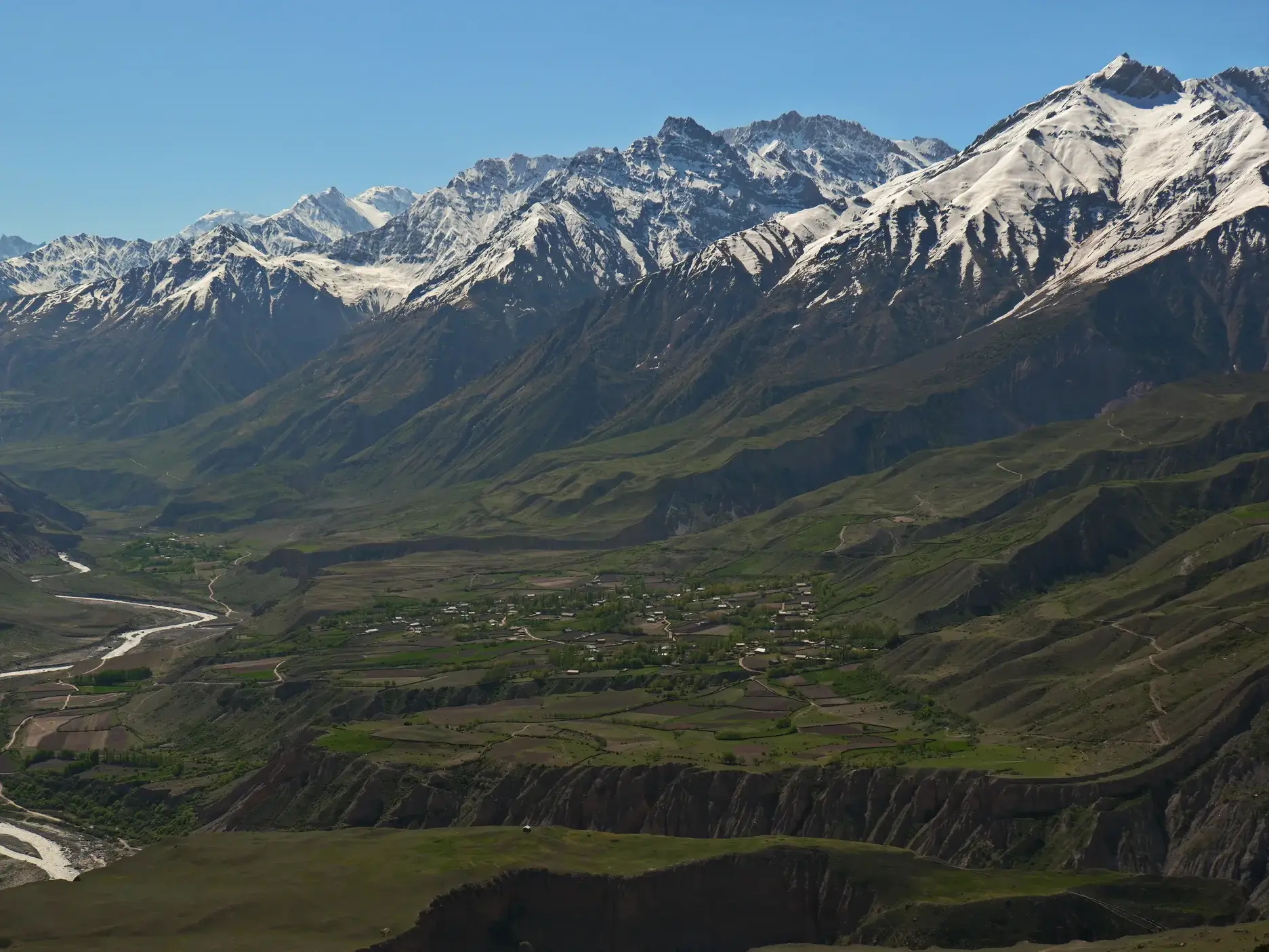 Majestätische, schneebedeckte Gipfel des Nordwest-Pamir thronen über dem grünen Rasht-Tal mit seinem Fluss in Tadschikistan.