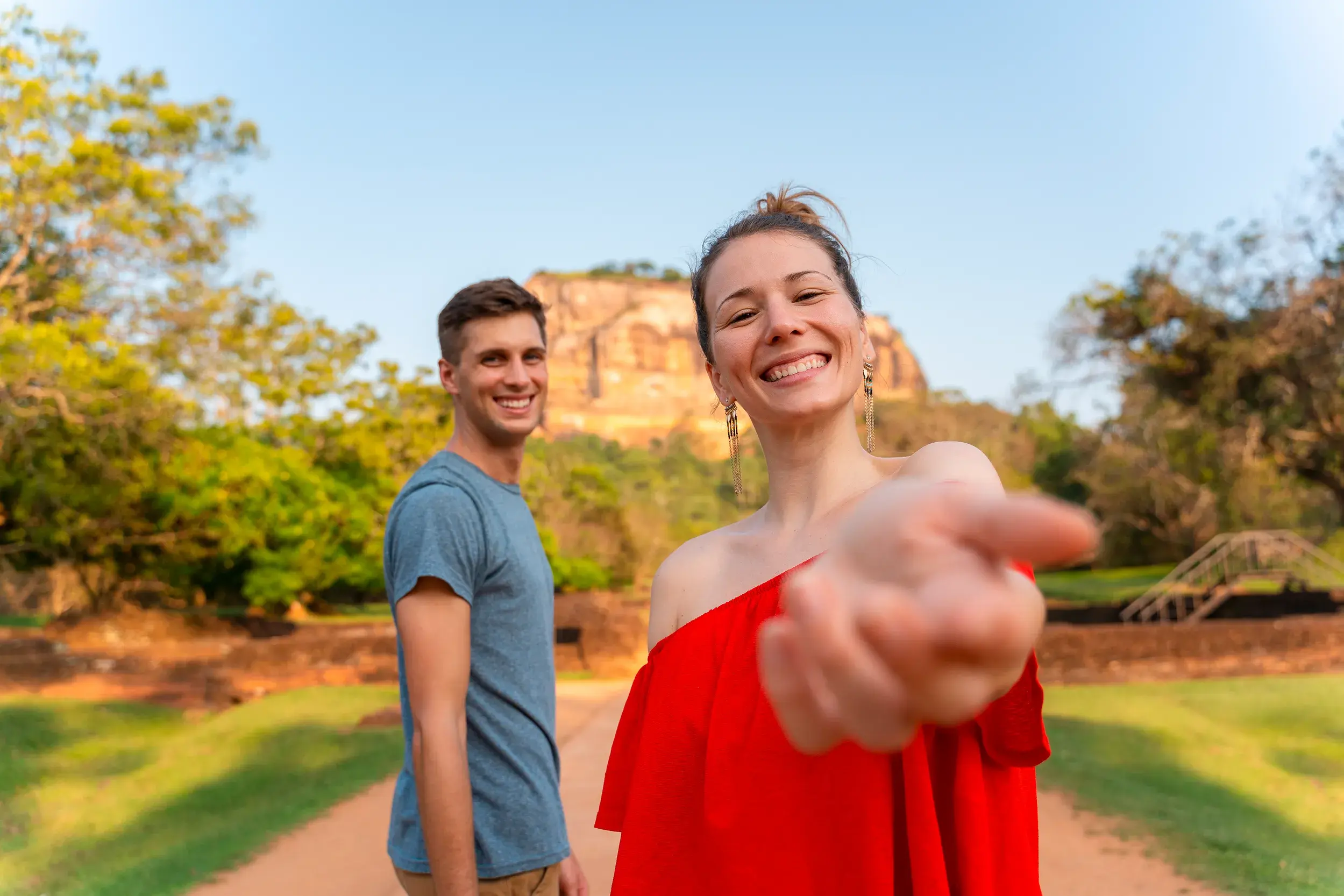 Eine junge Frau reicht ihre Hand auf einer Gruppenreise für junge Leute vor dem berühmten Sigiriya-Felsen in Sri Lanka.