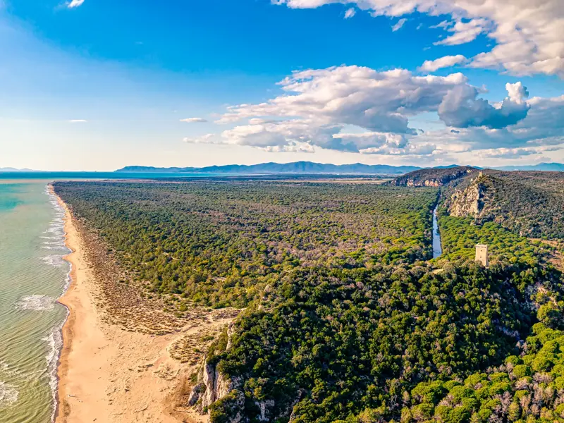 Weitläufiger Blick über den Parco Naturale della Maremma in der Toskana: Sandstrand, Meer, Pinienwälder und ein Wachturm.
