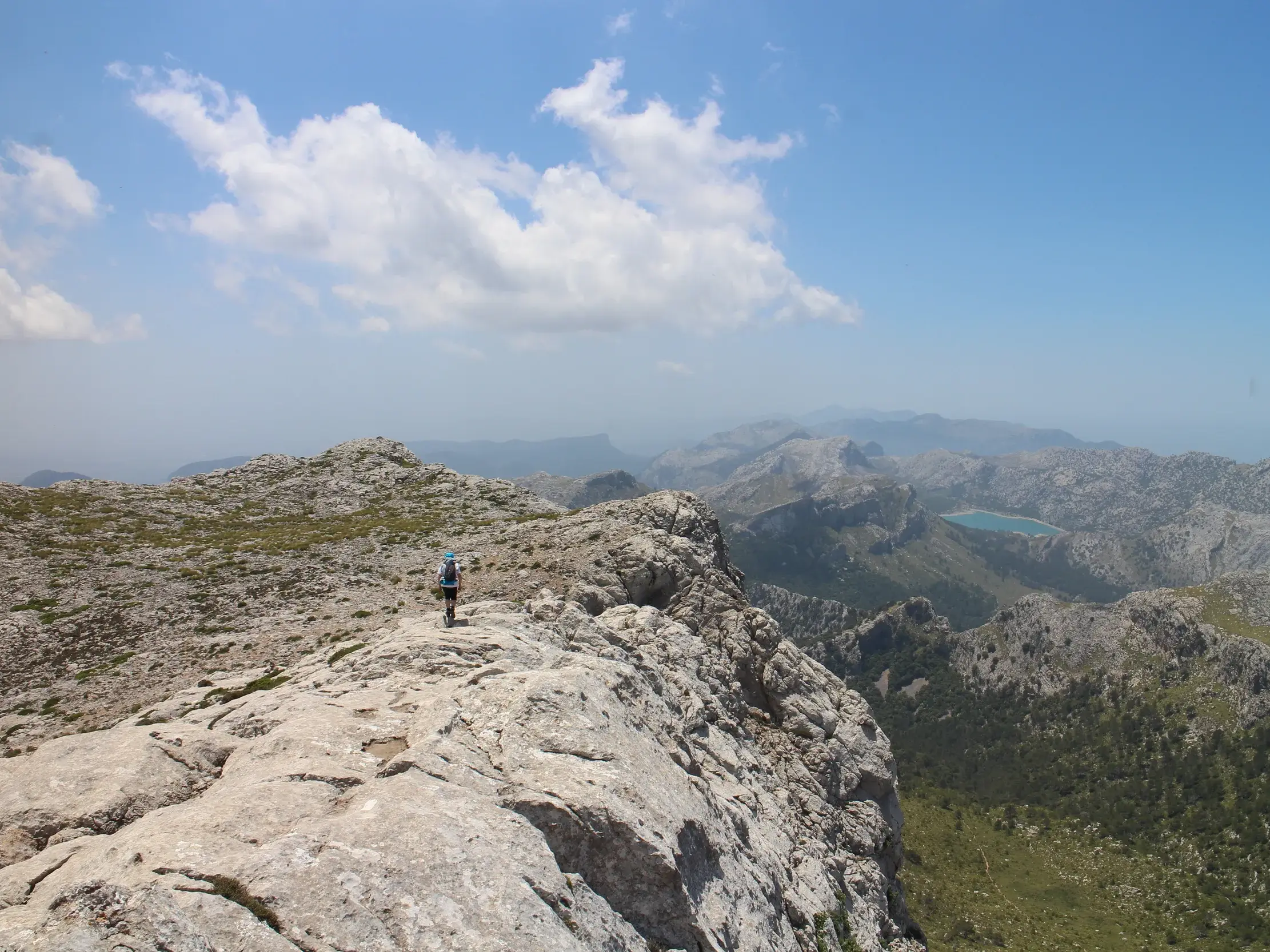 Wanderer auf dem felsigen Gipfelgrat des Puig de Massanella mit Panoramablick über die Serra de Tramuntana auf Mallorca.