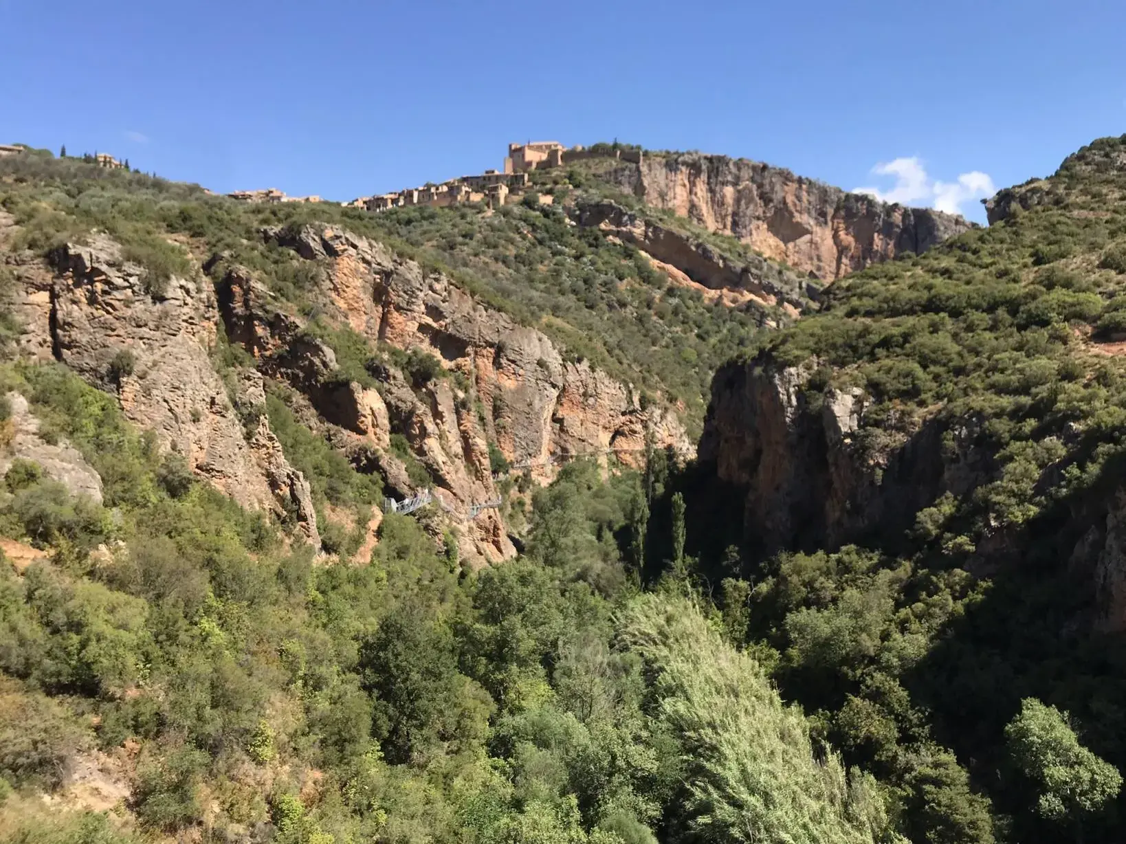 Majestätischer Blick in die tiefgrüne, bewaldete Schlucht des Río Verde in der Sierra de Guara, überragt vom Bergdorf Alquézar.