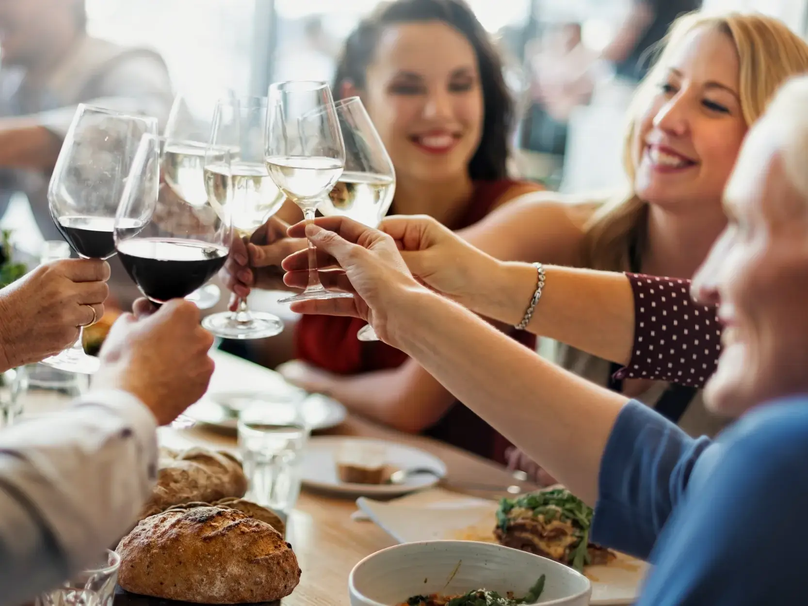 Eine Reisegruppe stößt beim Welcome-Dinner in Warschau fröhlich mit Rot- und Weißwein an und lernt sich dabei kennen.