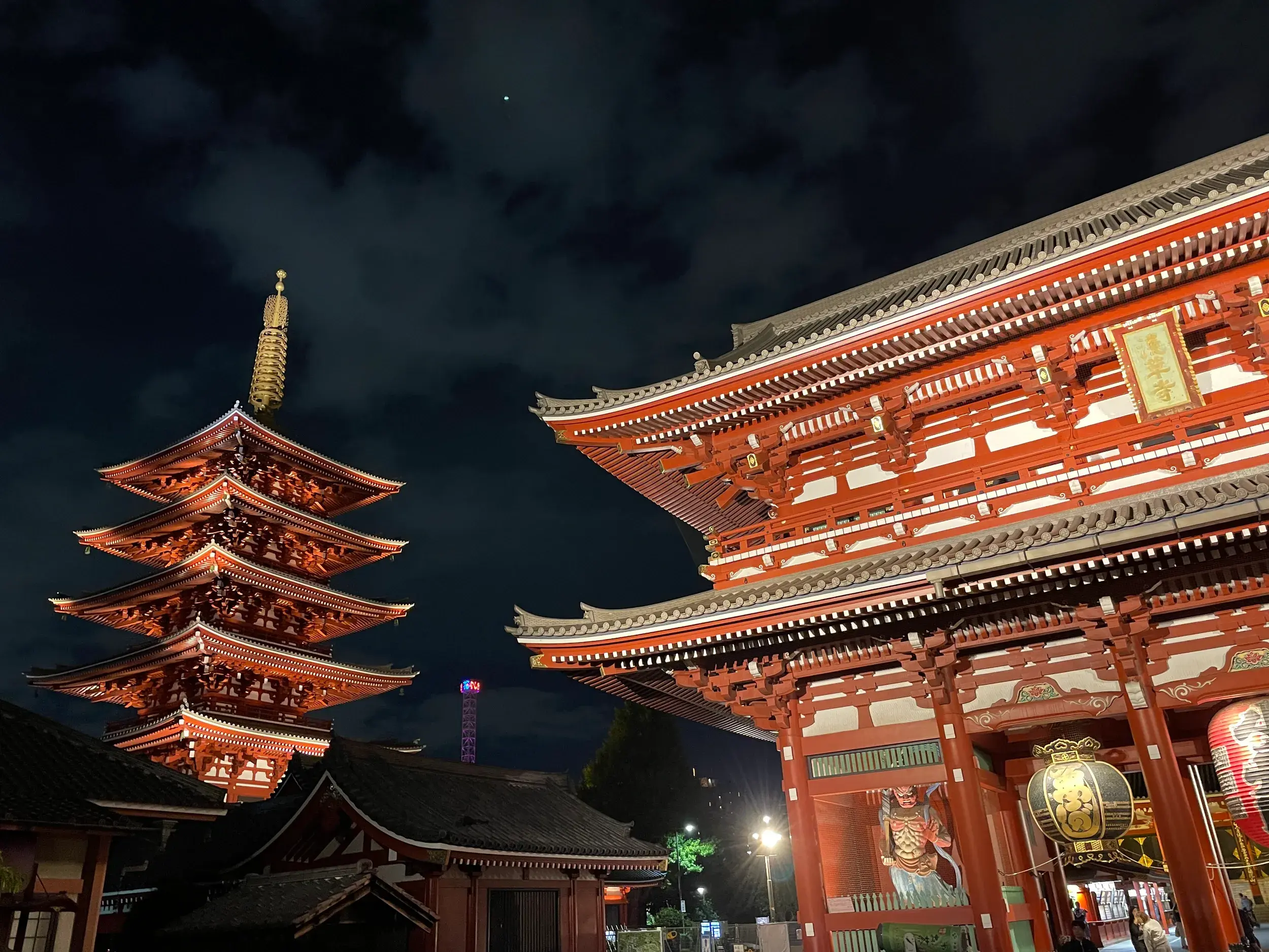 Die rote Pagode und das Eingangstor des Asakusa-Kannon Tempels in Tokio leuchten eindrucksvoll am dunklen Nachthimmel.