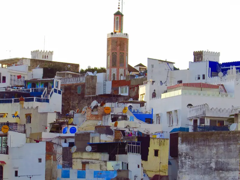 Das Minarett der Großen Moschee ragt über die weiß-blauen Häuser der historischen Medina von Tanger in Nordmarokko.