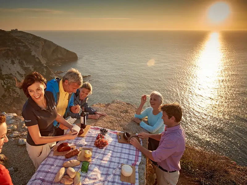 Studiosus-Reisegruppe bei einem Picknick an den Klippen der Algarve bei Sonnenuntergang
