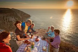 Studiosus-Reisegruppe bei einem Picknick an den Klippen der Algarve bei Sonnenuntergang