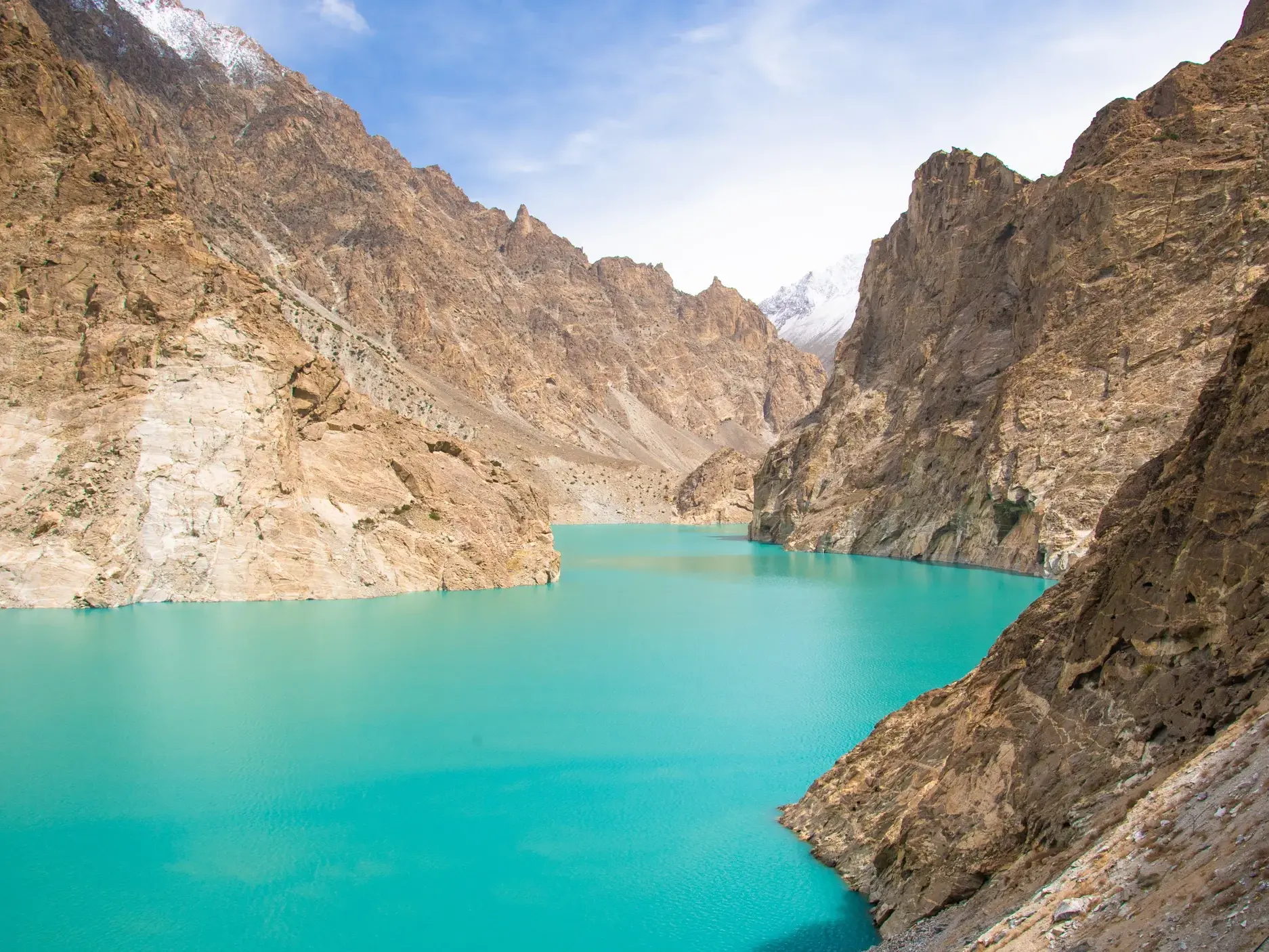 Leuchtend türkisfarbener Attabad-See, der sich durch die karge, felsige Berglandschaft des Hunzatals in Pakistan schlängelt.