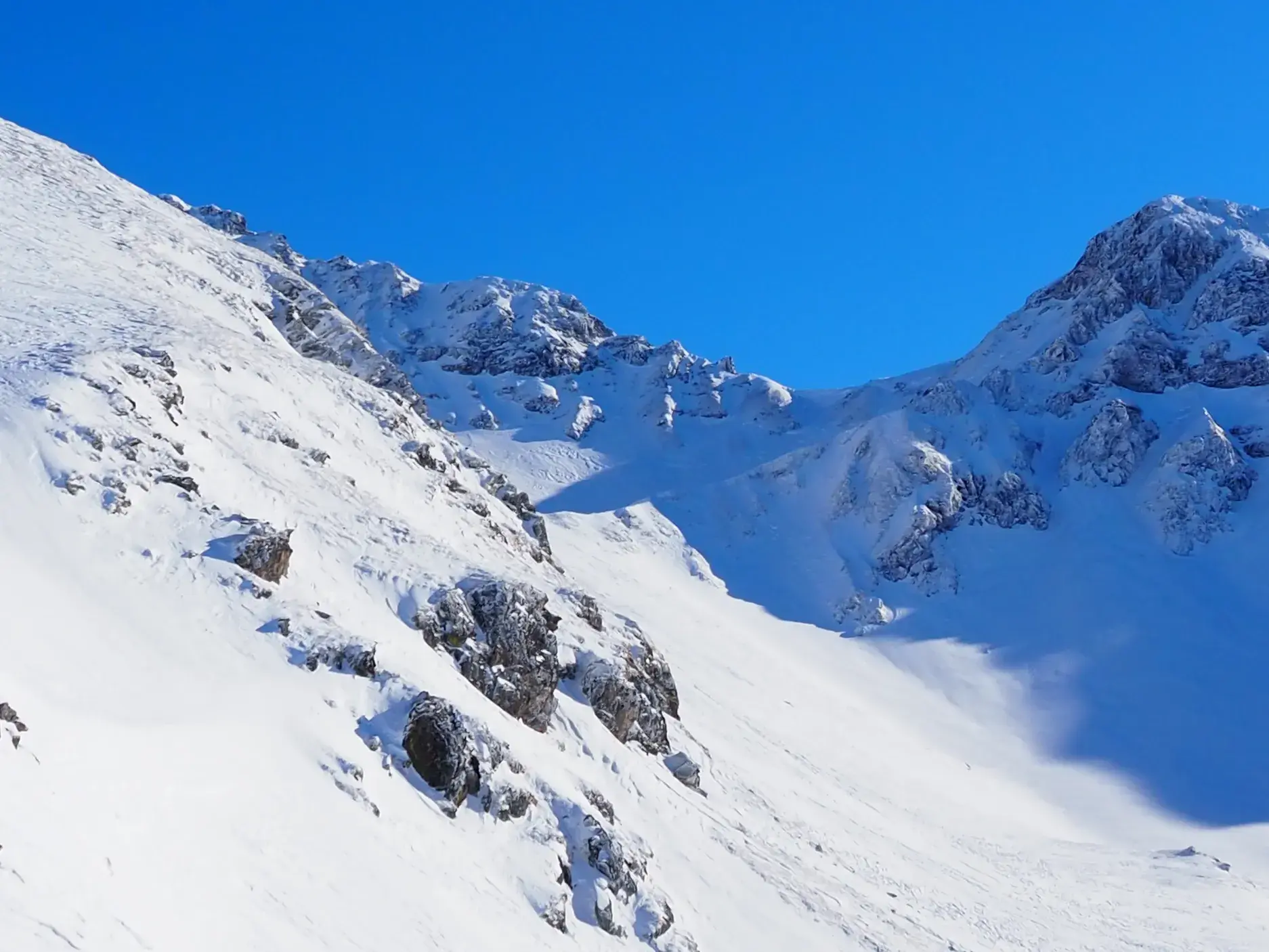 Schroffe, schneebedeckte Gipfel des Sharr-Gebirges im Kosovo unter strahlend blauem Himmel bei einer Skitour.