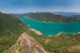 Zwei Wanderer auf dem felsigen Gipfel des Mamanguá Peak genießen den Panoramablick auf die türkise Bucht von Mamanguá.