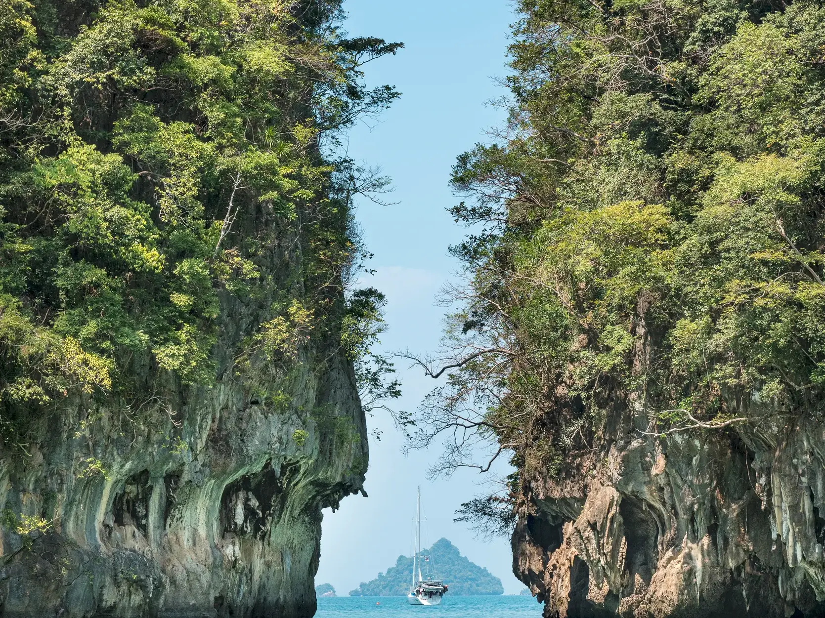 Enge Passage zwischen zwei hohen, von Dschungel bewachsenen Karstfelsen während einer Bootstour in der Phang-Nga-Bucht.