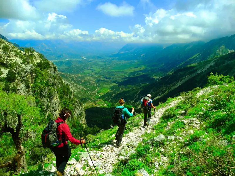 Eine Hauser-Wandergruppe auf einem felsigen Pfad mit Panoramablick über das Shushica-Tal im albanischen Küstengebirge.