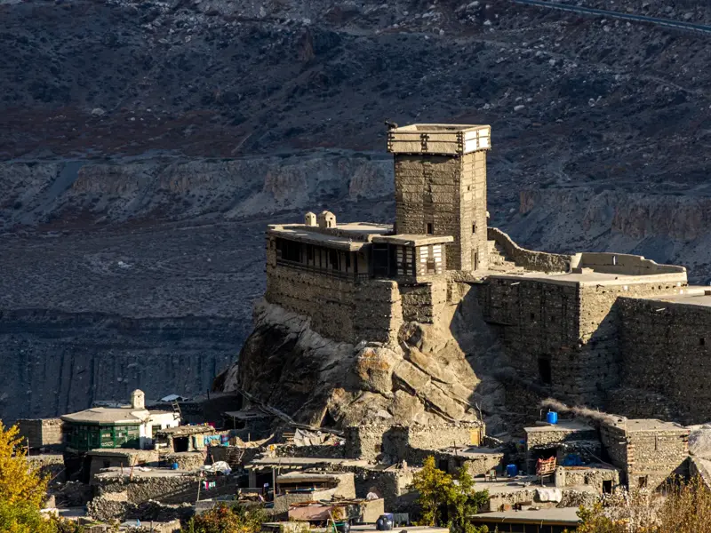 Das alte Baltit Fort in Karimabad im Hunzatal thront auf einem Felsen über einem Dorf vor einer steilen Bergkulisse.