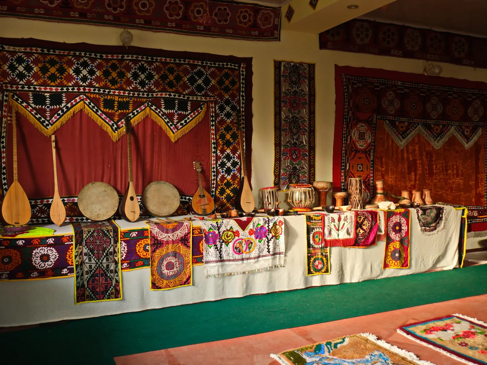 Ausstellung tadschikischer Kultur: Traditionelle Musikinstrumente, Trommeln und bunte Textilien in einem Museum in Tadschikistan.