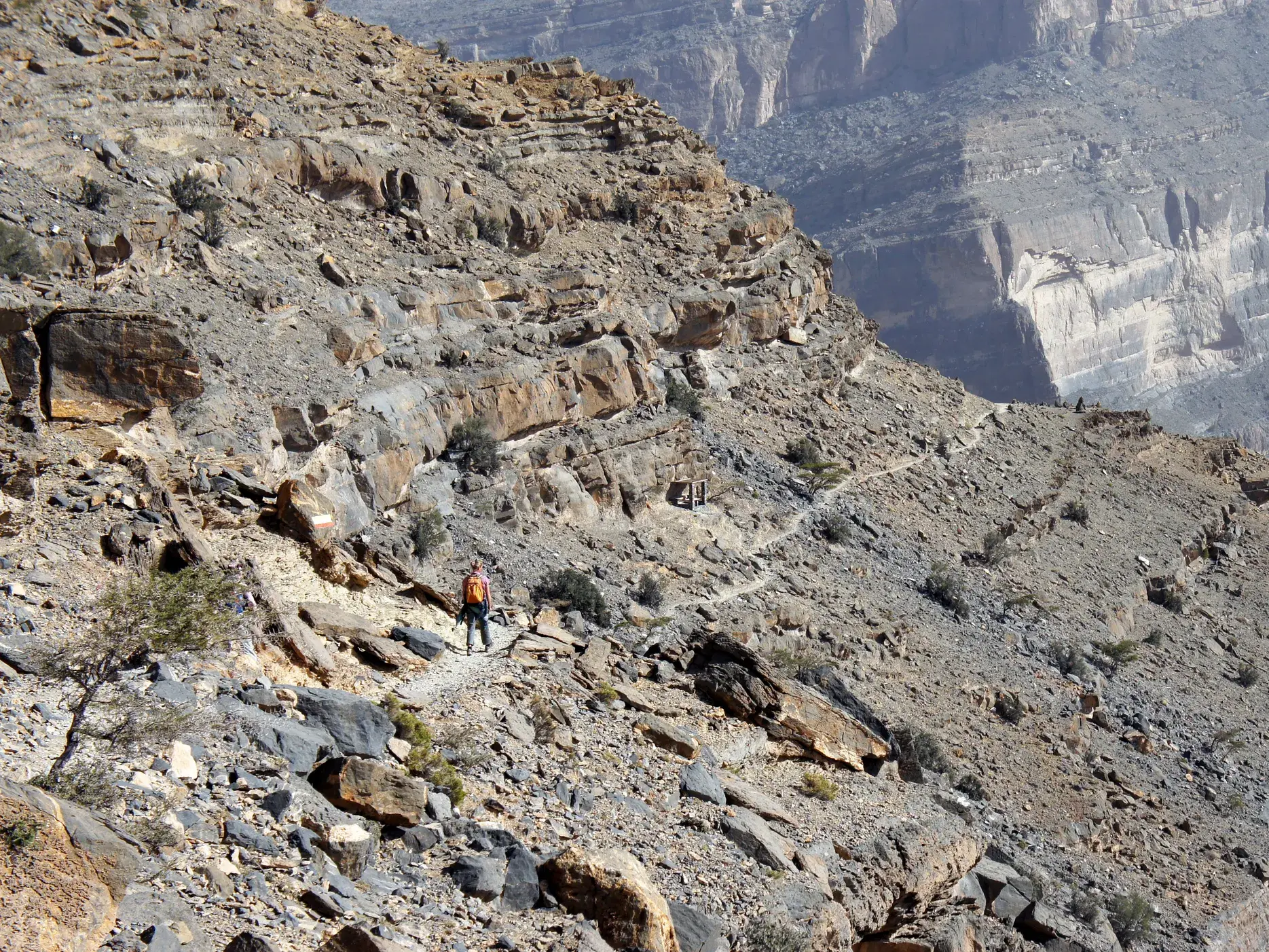 Ein Trekking-Teilnehmer wandert auf dem ausgesetzten Balcony Walk hoch über dem tiefen Canyon Wadi Ghul am Jebel Shams im Oman.