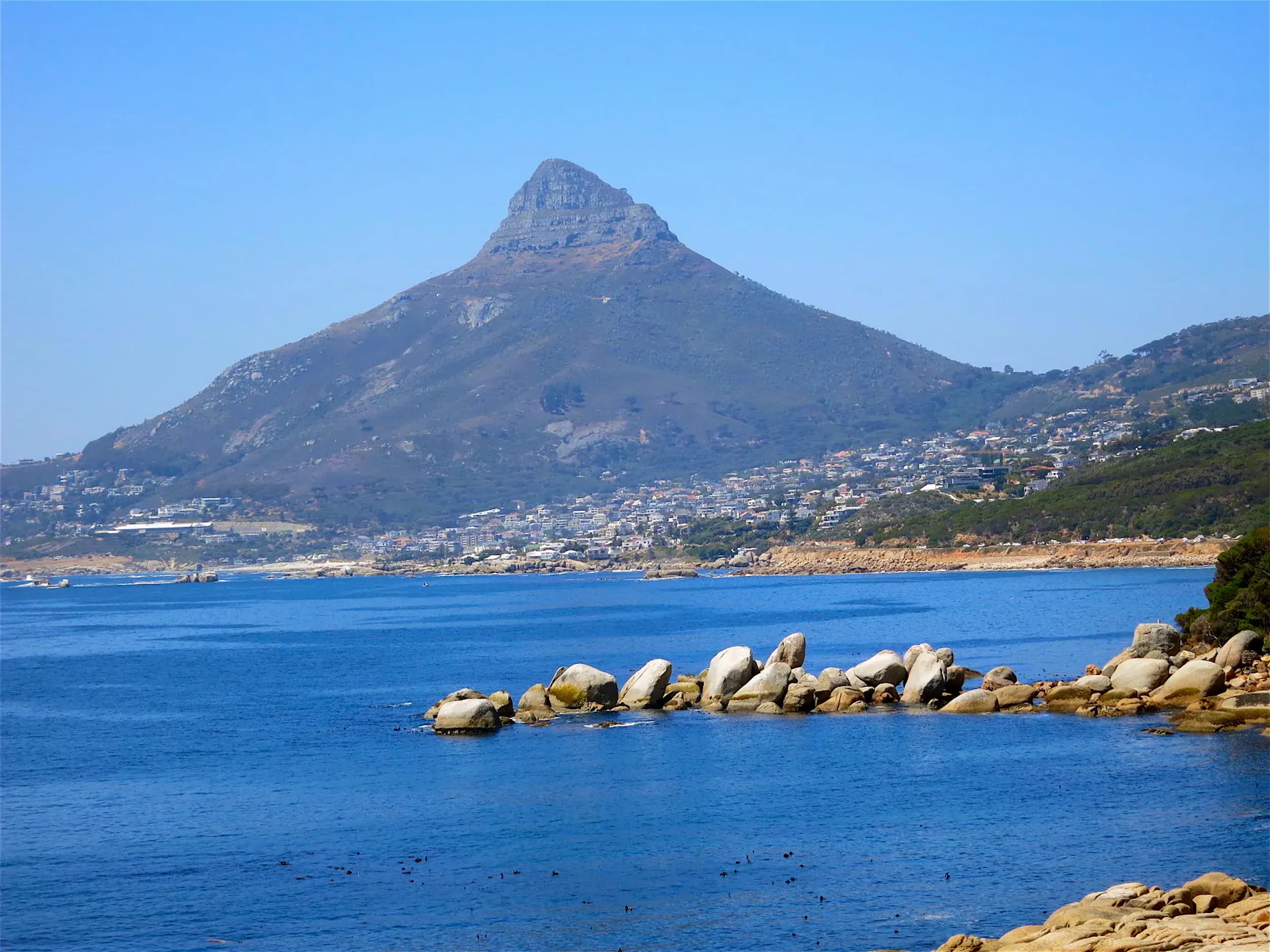 Blick über den blauen Atlantik auf den Lion's Head und die Küstenstadt Kapstadt an einem sonnigen Tag in Südafrika.