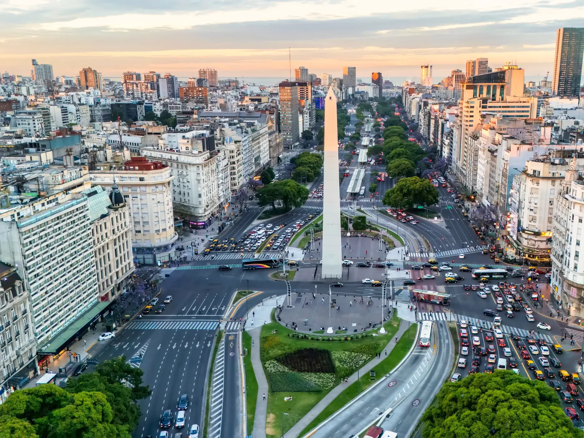 Luftaufnahme des Obelisken von Buenos Aires an der belebten Avenida 9 de Julio bei Sonnenuntergang mit der weiten Skyline.