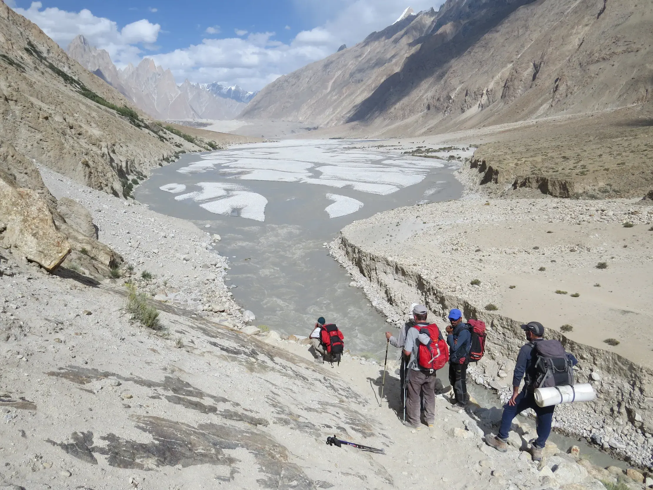 Eine Wandergruppe auf einem schmalen Pfad über dem Braldu-Fluss während einer Trekkingreise durch das Karakorum-Gebirge in Pakistan.