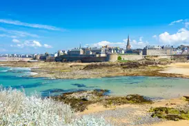 Blick über das türkisfarbene Meer bei Ebbe auf die historische Altstadt und die Stadtmauern der Korsarenstadt St-Malo.