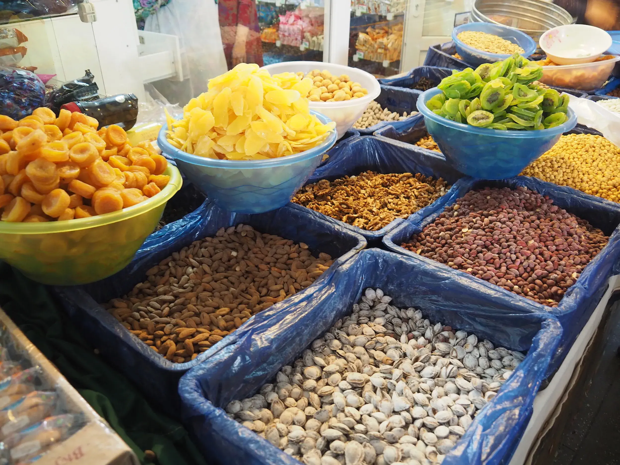 Bunte Schalen und Kisten mit Trockenfrüchten, Mandeln und Nüssen auf dem großen Basar von Samarkand in Usbekistan.