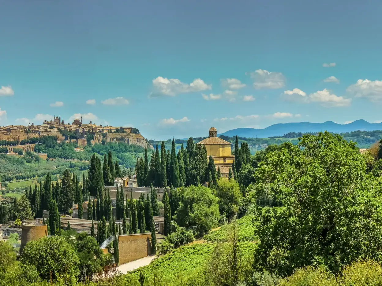 Wanderung in Umbrien mit Panoramablick auf die Etruskerstadt Orvieto, umgeben von grünen Hügeln und Zypressen.