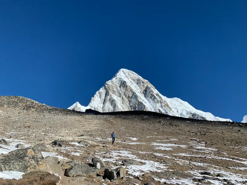 Ein Wanderer auf dem Trekkingpfad nahe Kala Pattar mit Blick auf den majestätischen, schneebedeckten Gipfel des Pumori.