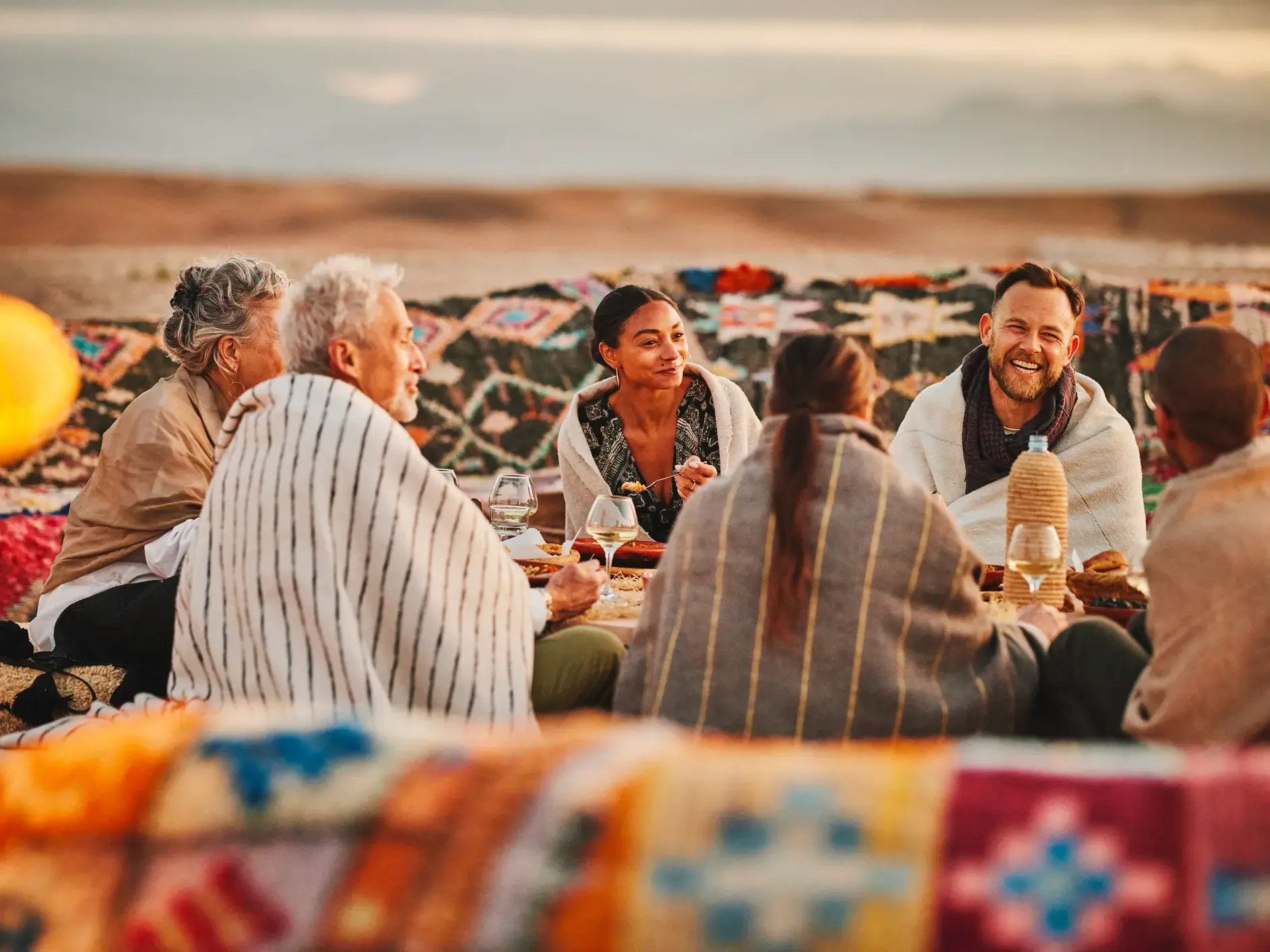 Reisegruppe genießt ein traditionelles Abendessen in gemütlicher Runde am Rande der Sahara in Marokko.