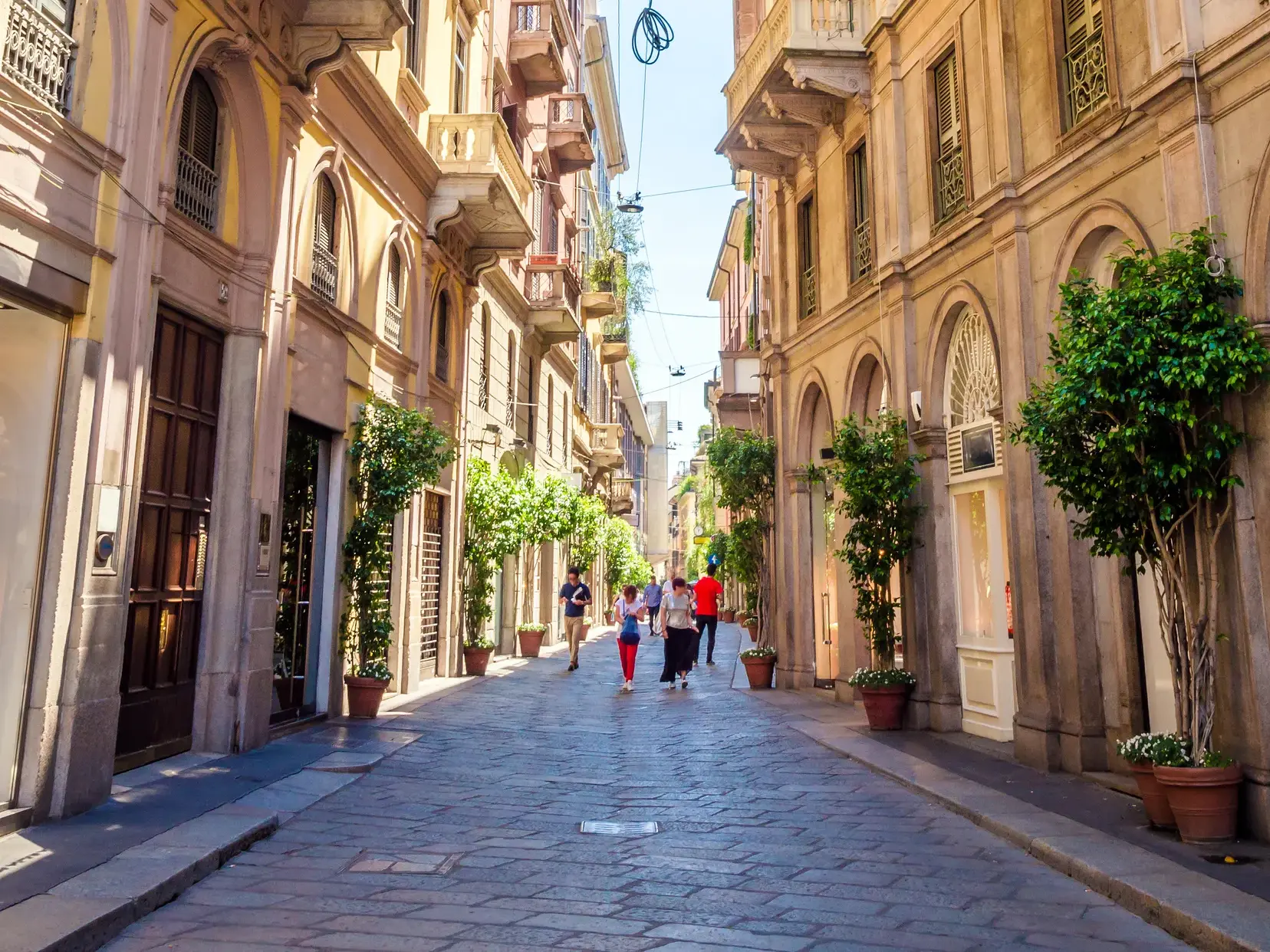 Passanten flanieren durch eine gepflasterte Gasse mit Boutiquen im Brera-Viertel in Mailand.