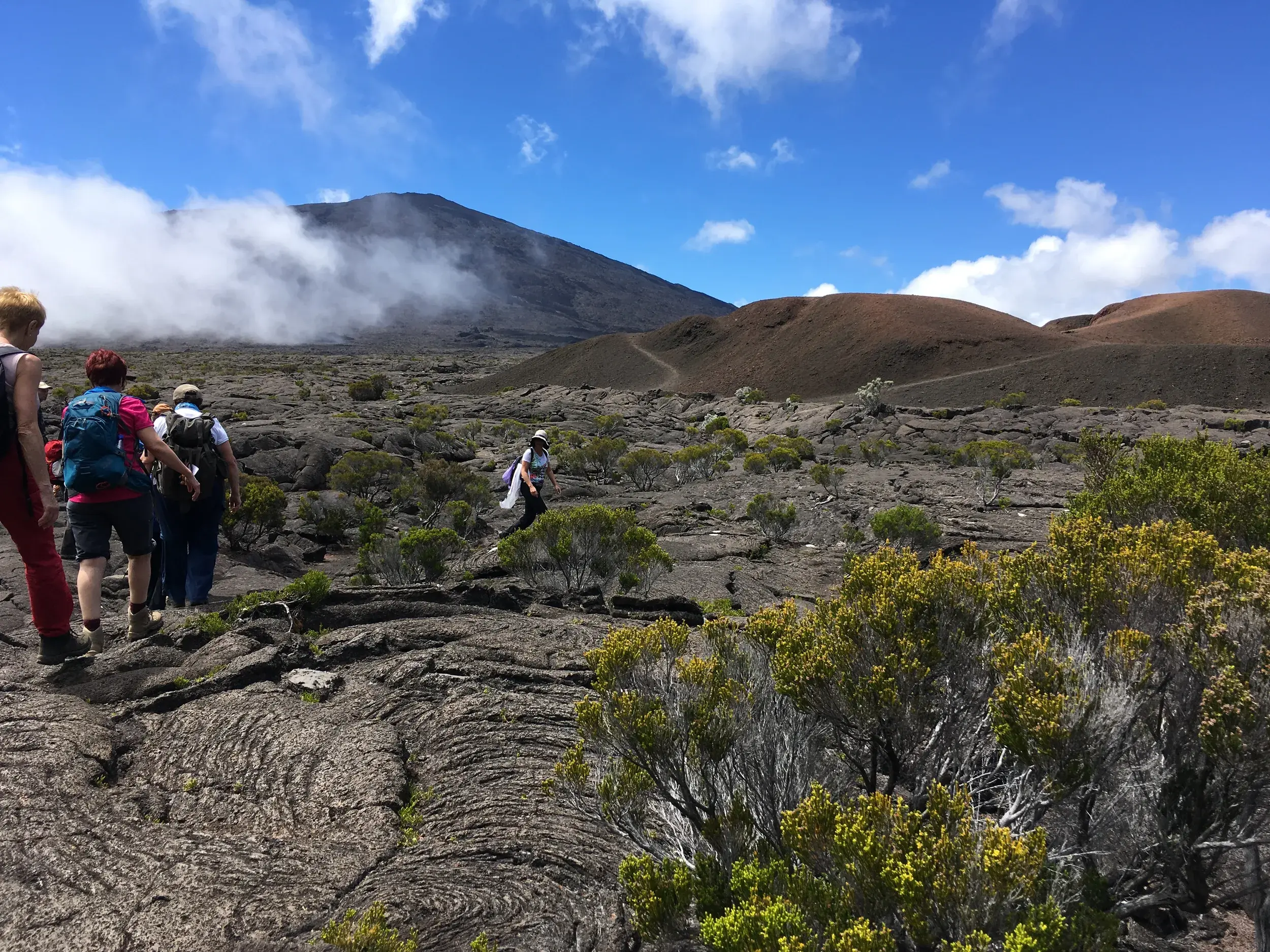 Eine kleine Wandergruppe durchquert die weite, mondartige Vulkanlandschaft des Piton de la Fournaise auf La Réunion.