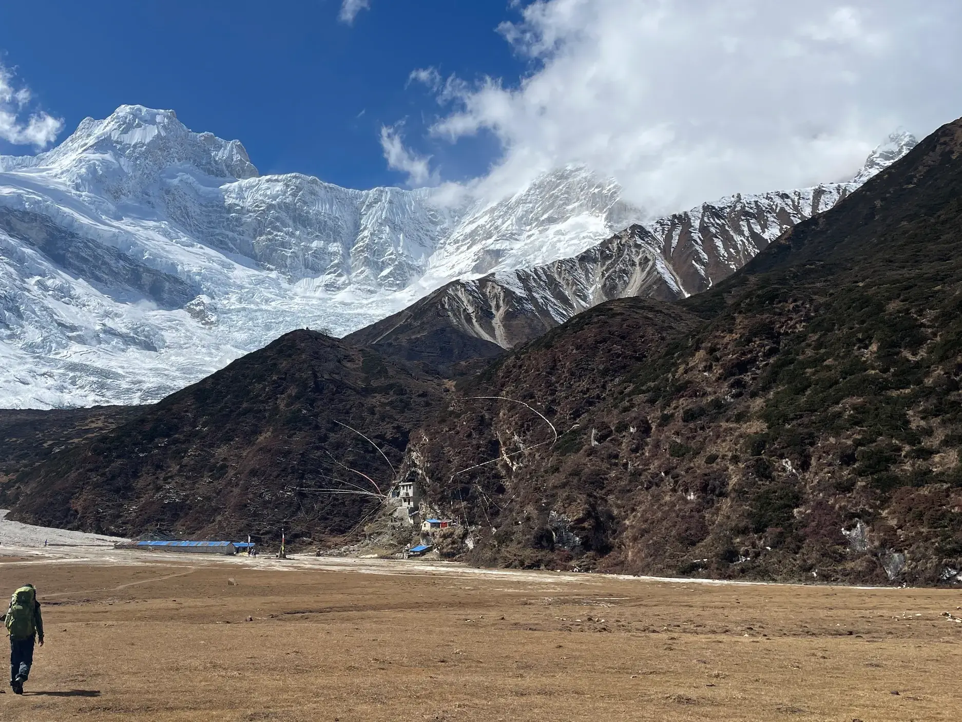 Ein Trekking-Reisender wandert durch das weite Hochtal bei Sama Gaon mit Blick auf die vergletscherte Manaslu-Bergkette in Nepal.