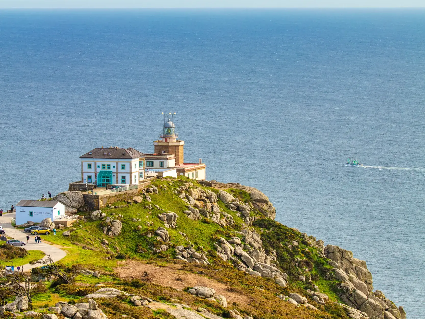 Der Leuchtturm am Kap Finisterre thront auf einer grünen Felsklippe über dem Atlantik, dem Ziel vieler Jakobsweg-Pilger.