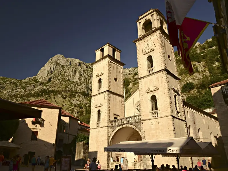 Die romanische Sankt-Tryphon-Kathedrale in der Altstadt von Kotor vor der imposanten Bergkulisse des Lovćen-Gebirges.